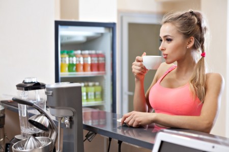 Sportive woman with cup in the gym bar