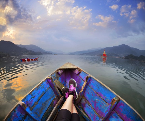 Feet luing in the boat ,landscape with  Himalaya mountains and c